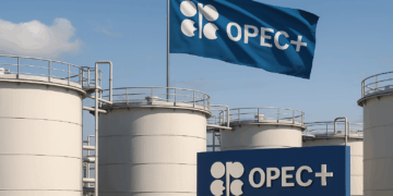 OPEC+ tanques de petróleo blancos con bandera azul de OPEC+ ondeando al fondo horizontal