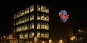 Fachada iluminada de la planta TSMC en Taiwán por la noche, reflejando actividad operativa intensa