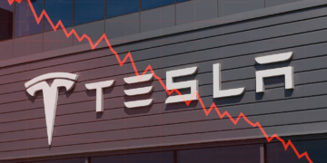 Fachada de Tesla con gráfica roja descendente sobre logo tesla