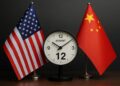 Primer plano de banderas de EE.UU. y China enfrentadas junto a reloj marcando el 12 de agosto.