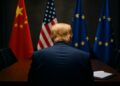 Donald Trump observa sala con banderas de China, EE.UU. y UE durante negociación.