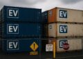 Contenedores marcados con “ vehículos eléctricos ” apilados en un puerto de EE.UU., con vallas y señales de advertencia visibles.