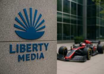 Fachada de Liberty Media con logotipo visible y auto de Fórmula 1 desenfocado al fondo.