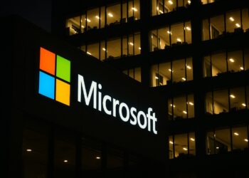 Fachada nocturna de un edificio de Microsoft con logo iluminado y ventanas encendidas.