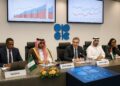 Delegados de la OPEC en sala de conferencias con gráficos de producción petrolera proyectados.