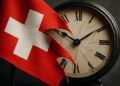 Primer plano de bandera suiza rasgada con reloj antiguo y detenido en segundo plano