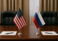 Mesa formal de negociación con banderas de Estados Unidos y Rusia, dos hojas y bolígrafos