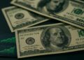 Fotografía macro de varios billetes de dólar sobre una mesa de operaciones financieras.