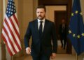 Fotografía de Zelenskyy genérico caminando serio hacia una sala oficial con banderas institucionales