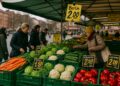 Puestos de verduras en mercado callejero de Berlín con precios visibles en letreros amarillos de inflación