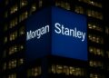 Edificio de Morgan Stanley en Nueva York con logo azul iluminado de noche y oficinas encendidas