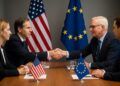 Representantes de Estados Unidos y Europa se dan la mano en una mesa de negociación con banderas oficiales