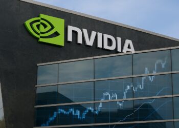 Fachada de sede Nvidia con logo verde y reflejo de gráficos bursátiles en vidrio