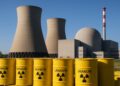 Planta de energía nuclear con cielo despejado y bidones amarillos de uranio apilados
