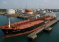  Vista aérea de terminal petrolera en India con tanques de almacenamiento y barco descargando crudo en muelle