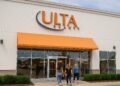 Fachada horizontal de una tienda Ulta Beauty con letrero naranja y clientes accediendo al interior