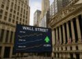 Vista de Wall Street con pantalla que muestra gráficos de índices bursátiles