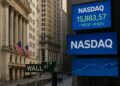 Imagen de Wall Street con letrero de Nasdaq en pantallas electrónicas mostrando cifras en aumento