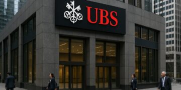 Vista de la fachada de UBS en un distrito financiero con logo rojo destacado sobre el edificio