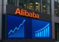 Fachada moderna de edificio de Alibaba con pantallas digitales que muestran gráficos financieros en alza