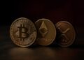 Monedas físicas de Bitcoin, Ethereum y XRP en mesa metálica, representando la caída del mercado cripto.