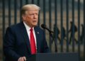 Donald Trump en podio con fondo migratorio, reflejando impacto de la tarifa en visas H-1B.