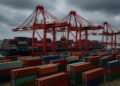 Vista de contenedores apilados en un puerto chino con grandes grúas rojas en operación
