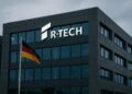 Fachada de edificio corporativo de Rheinmetall en Alemania con logotipo R-Tech iluminado y bandera alemana ondeando