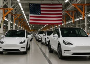 Fábrica en Estados Unidos con autos eléctricos ( EV )blancos en línea de producción bajo una bandera estadounidense