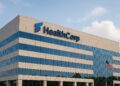 Fachada de edificio corporativo HealthCorp en EE.UU. con logotipo iluminado y bandera al frente