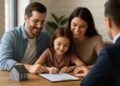 Familia con hija pequeña firma documentos para compra de vivienda en oficina inmobiliaria en EE.UU.