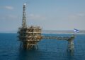 Plataforma marítima de chevron de gas natural en el Mediterráneo con bandera de Israel y costa al fondo