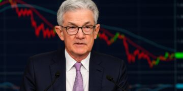 Jerome Powell durante una conferencia de prensa con gráficos de mercado proyectados detrás