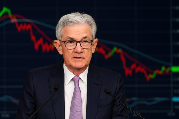 Jerome Powell durante una conferencia de prensa con gráficos de mercado proyectados detrás