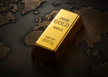 Lingotes de oro sobre un mapa mundial metálico, simbolizando proyecciones globales del metal.