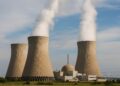 Vista horizontal de una planta nuclear en operación con tres torres de enfriamiento emitiendo vapor