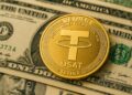 Moneda dorada de Tether sobre billetes de dólar, simbolizando el lanzamiento del nuevo token USAT