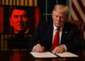 Donald Trump firma un decreto en el Despacho Oval mientras una pantalla muestra el rostro pixelado de Ronald Reagan.