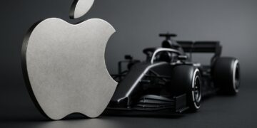 Logo metálico de Apple frente a un monoplaza de Fórmula 1 bajo luz natural de estudio.