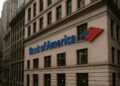 Edificio de Bank of America con su logotipo en una calle tipo Wall Street rodeada de rascacielos