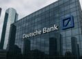 Edificio de vidrio con el logo de Deutsche Bank visible en entorno urbano financiero