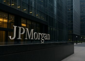 Edificio de vidrio con el logo de JPMorgan visible en distrito financiero con reflejos urbanos