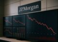 Pantallas con gráficos bursátiles en rojo dentro de una oficina de JPMorgan con su logo visible