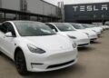 Fila de vehículos Tesla estacionados en planta de producción tras aumento de entregas trimestrales.