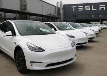 Fila de vehículos Tesla estacionados en planta de producción tras aumento de entregas trimestrales.