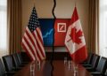 Banderas de Estados Unidos y Canadá separadas por línea divisoria en sala diplomática con mesa y cortinas beige