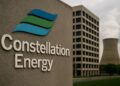 Logo de Constellation Energy en gran tamaño frente a planta nuclear y edificio corporativo.