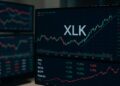 Monitores con gráficos bursátiles de XLK y tickers tecnológicos en verde y rojo
