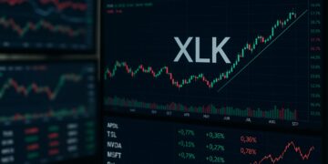 Monitores con gráficos bursátiles de XLK y tickers tecnológicos en verde y rojo