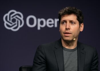 Sam Altman habla en un panel con el logo de OpenAI proyectado en pantalla LED detrás